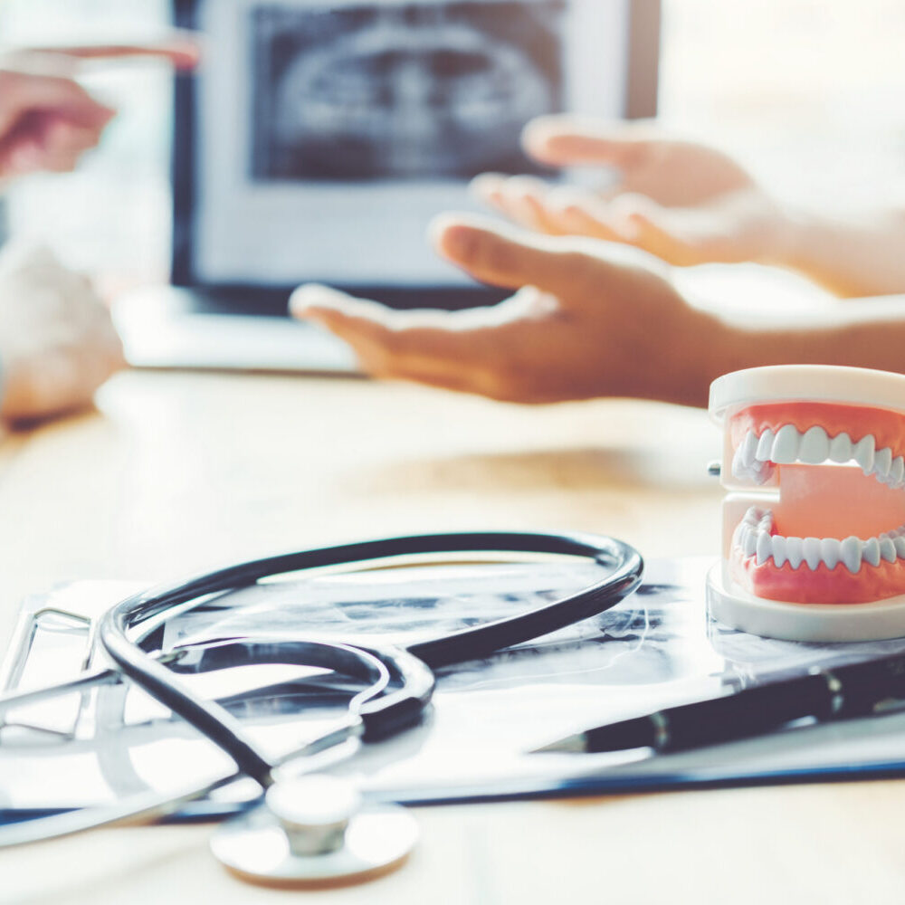 Dentist talking to male patient and presenting results on Dental x-ray film About the problem of the patient in dental office